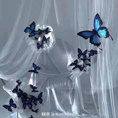 some blue butterflies are flying in the air over a white cloth covered bed with sheer curtains