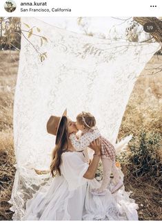 a woman holding a small child in her arms while sitting on top of a blanket