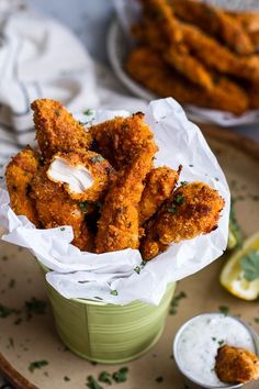 some fried food is in a small green bowl on a plate with lemon wedges