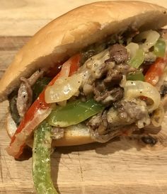 a close up of a sandwich on a cutting board with meat and vegetables in it