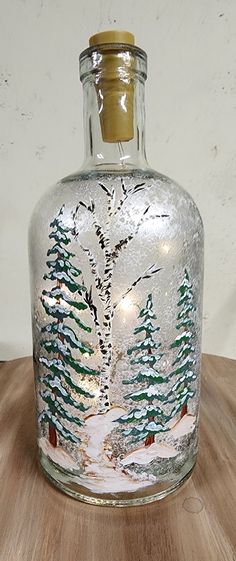 a glass bottle with trees painted on it