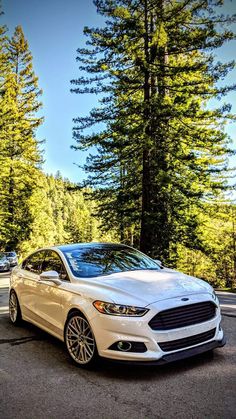 a white car parked in front of some trees