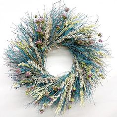 a blue and white wreath with flowers on it's end, sitting against a white wall