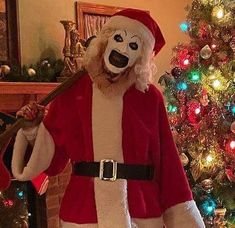 a man dressed as santa claus holding a baseball bat in front of a christmas tree