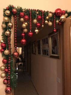 a hallway decorated for christmas with red and gold ornaments hanging from the side of it