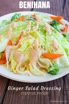 a white plate topped with lettuce and carrots covered in dressing next to broccoli