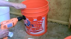 an orange bucket being used to paint a wall