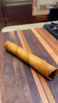 a piece of food sitting on top of a wooden cutting board next to a stove