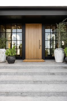 two planters are sitting on the steps in front of a door that is open