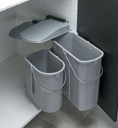 two trash cans sitting next to each other on top of a white shelf in a room