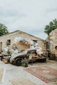 an old car parked in front of a house with balloons on the door and decorations around it