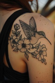 a woman's shoulder with a hummingbird and flowers tattoo on her left arm