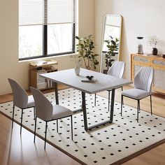 a dining room table with four chairs and a rug on the floor in front of it