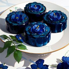 blue flowers on a white plate with gold trimmings and green leaves around them