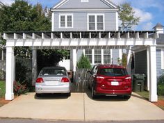 two cars parked in front of a house with a pergolan over the driveway