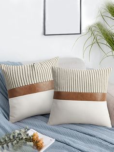 two pillows sitting on top of a bed next to a plant