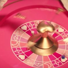 a pink and gold spinning wheel with hearts on it