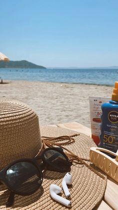 a hat, sunglasses and sunscreen on a beach