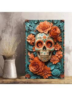 a skull with orange flowers on it sitting next to a vase and potted plant