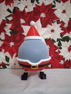 a red and blue santa hat sitting on top of a white bed next to a flowered wall