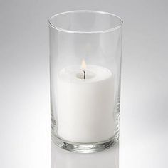 a white candle in a clear glass vase