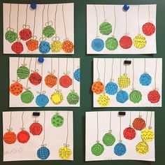 four cards with different colored balls hanging from strings on the wall next to each other