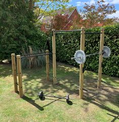 an outdoor gym in the middle of a yard with two squats and one pull up bar