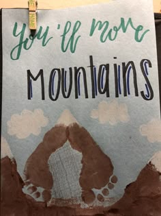 a sign that says you'll move mountains on the side of a building with footprints painted on it