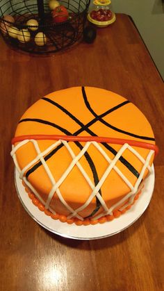 a basketball cake with white icing and black lines on the top is sitting on a wooden table