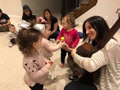 a group of women and children sitting on the floor playing with an object in front of them