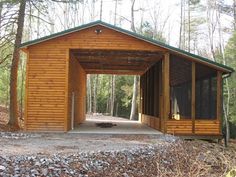 a wooden structure in the middle of a forest with rocks on the ground and trees around it