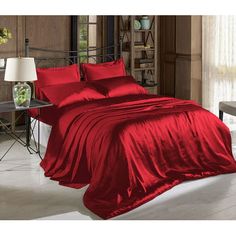 a bed with red sheets and pillows in a room