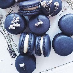 blue macaroons with white flowers on them sitting next to some branches and twigs