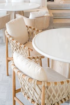 wicker chairs and tables in a room with white tile flooring, wood trimmings