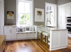 a kitchen with white cabinets and counter tops next to a window seat in front of an oven