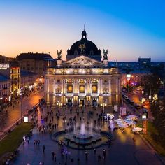 an aerial view of people walking around in front of a large building at night time