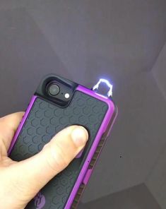 a person holding up a purple and black cell phone with a light coming out of it