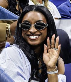 a woman wearing sunglasses and holding her hand up in the air at a tennis game