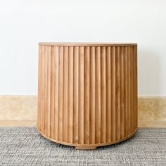 a round wooden planter sitting on top of a carpeted floor next to a wall