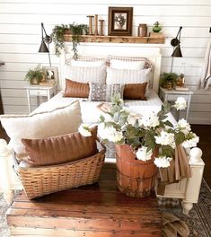 a bed with white flowers and brown pillows in a room next to a wooden floor