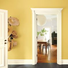 an open door leading to a dining room with yellow walls and wood flooring on the other side