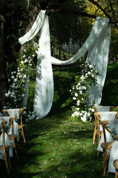 an outdoor wedding setup with white flowers and draping