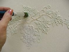 a person is using a pen to paint on a piece of paper with white lace