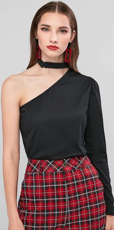 a woman wearing a red plaid skirt and black top with an asymmetrical neckline