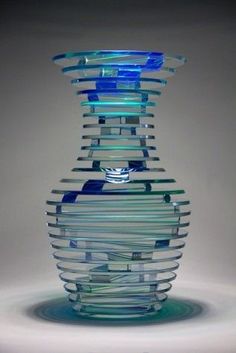 a glass vase sitting on top of a white table covered in blue and green stripes