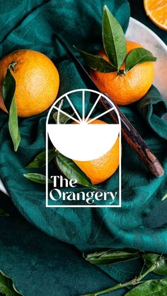 the orangery logo on a green cloth next to sliced oranges