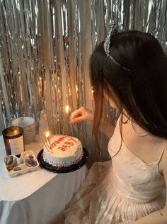 a woman blowing out candles on a birthday cake with the word happy written on it