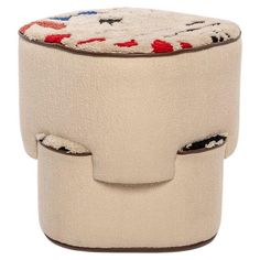 a white stool with red, white and blue designs on the seat is made out of felt