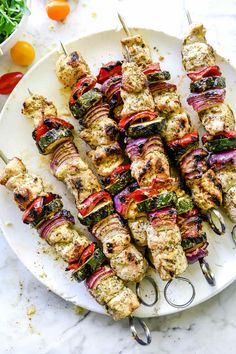 chicken kabobs on a white plate with tongs