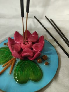 a blue plate topped with pink flowers and sticks